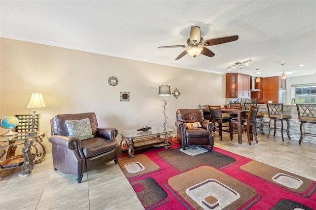 tiled living room featuring ceiling fan, ornamental molding, and track lighting