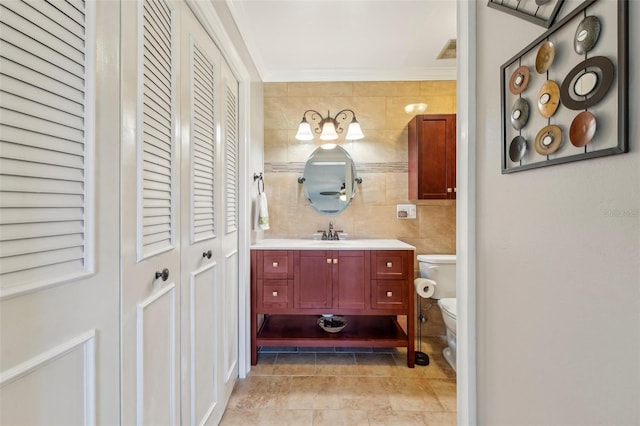 bathroom featuring tile walls, backsplash, vanity, ornamental molding, and toilet