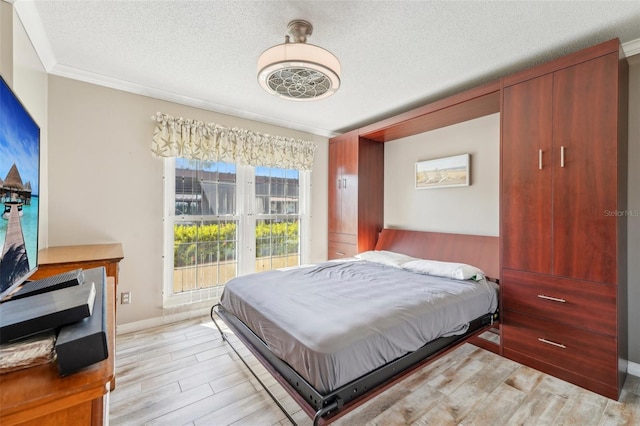 bedroom featuring crown molding, light hardwood / wood-style floors, and a textured ceiling