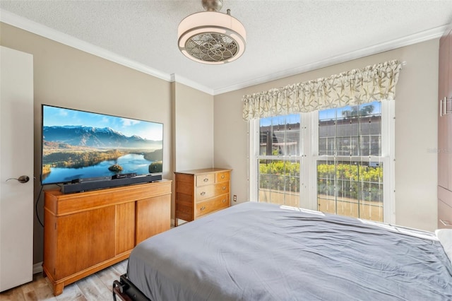 bedroom featuring crown molding, a textured ceiling, and light wood-type flooring