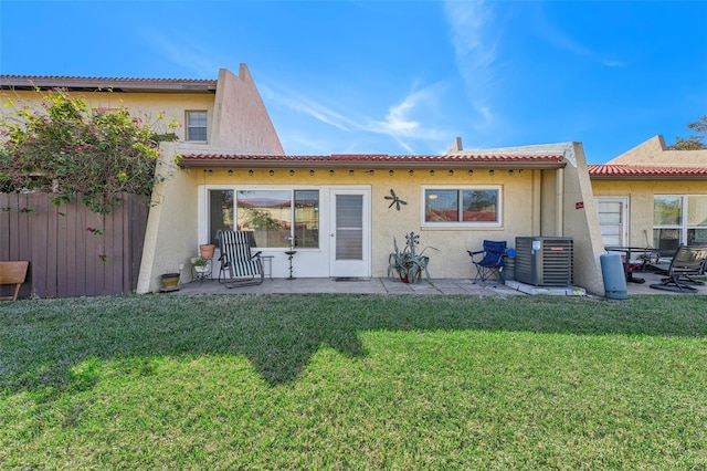 rear view of house featuring a lawn, central AC unit, and a patio area