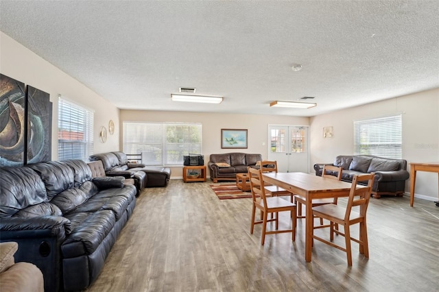 dining room with a textured ceiling, a healthy amount of sunlight, and light wood-type flooring