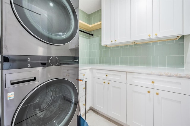 washroom with cabinets and stacked washer and clothes dryer