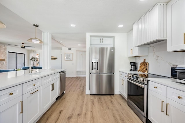 kitchen featuring white cabinetry, stainless steel appliances, hanging light fixtures, and light hardwood / wood-style flooring