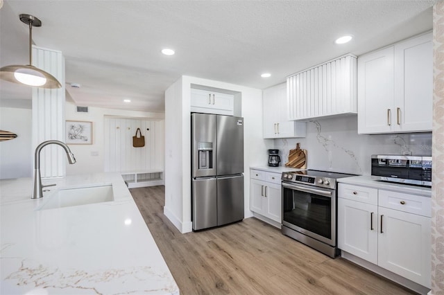 kitchen featuring pendant lighting, stainless steel appliances, sink, and white cabinets