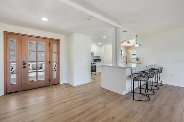 kitchen featuring decorative light fixtures, white cabinetry, a breakfast bar area, kitchen peninsula, and stainless steel appliances