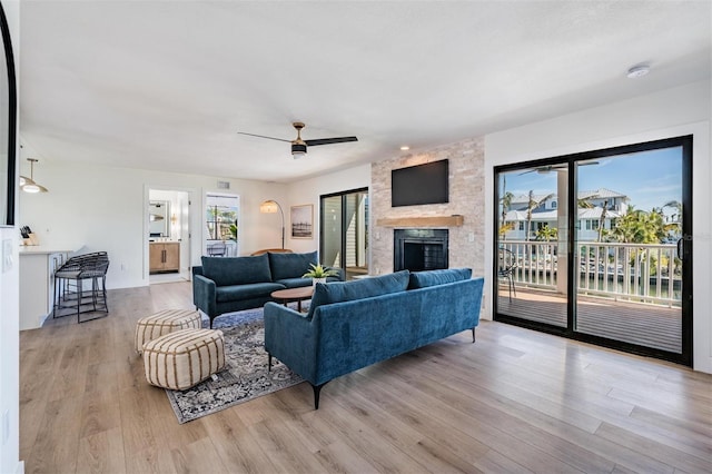 living room with ceiling fan, a fireplace, and light hardwood / wood-style flooring