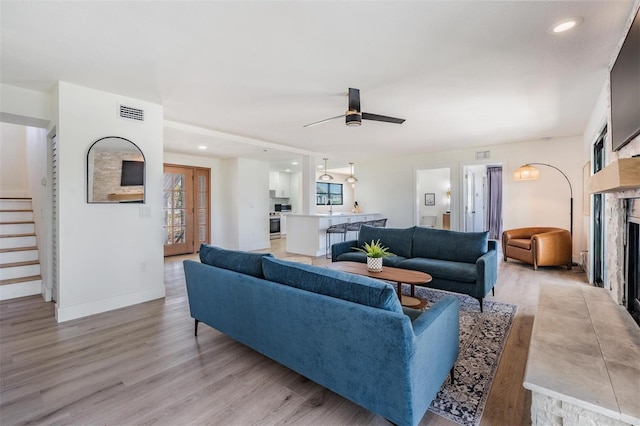 living room with plenty of natural light, light wood-type flooring, sink, and ceiling fan