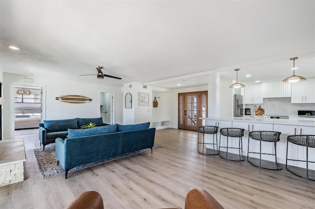 living room featuring sink, a wealth of natural light, light hardwood / wood-style floors, and french doors