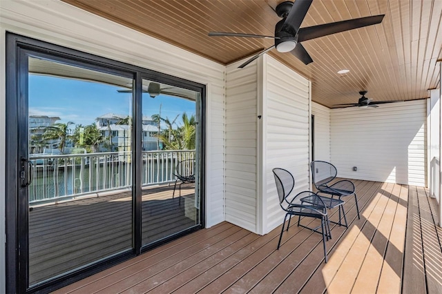 wooden terrace with a water view and ceiling fan