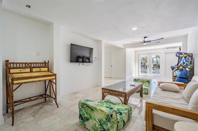 living room featuring ceiling fan, a textured ceiling, and french doors