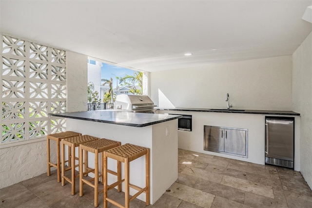 kitchen with sink, stainless steel refrigerator, and a breakfast bar