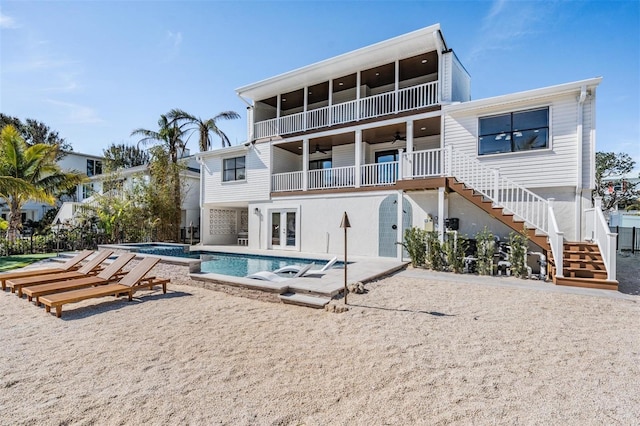 rear view of property with french doors, a patio area, a balcony, ceiling fan, and a swimming pool with hot tub