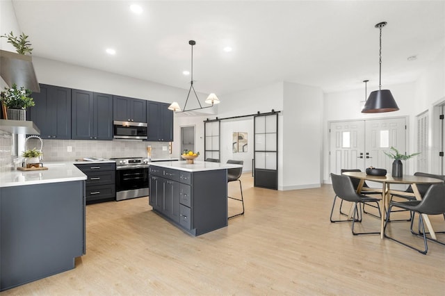 kitchen with backsplash, hanging light fixtures, a center island, stainless steel appliances, and a barn door