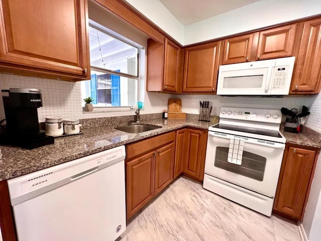 kitchen with tasteful backsplash, white appliances, dark stone counters, and sink