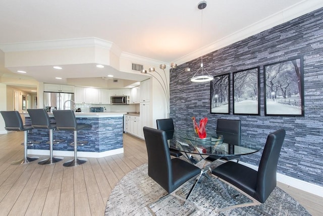 dining space with crown molding and light hardwood / wood-style flooring