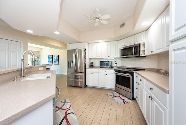 kitchen featuring tasteful backsplash, sink, white cabinets, and appliances with stainless steel finishes