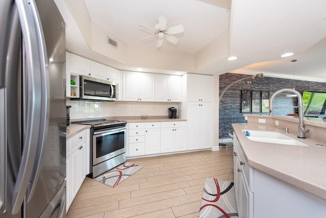 kitchen with pendant lighting, sink, ceiling fan, stainless steel appliances, and white cabinets