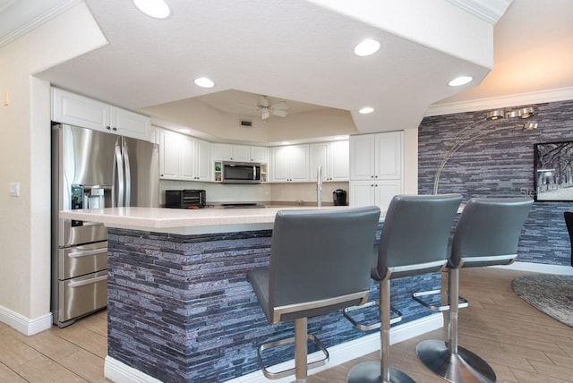 bar with appliances with stainless steel finishes, white cabinetry, sink, ornamental molding, and light hardwood / wood-style floors