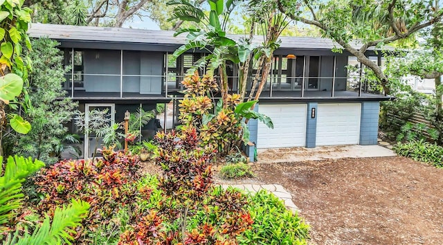 rear view of property featuring a garage and a sunroom