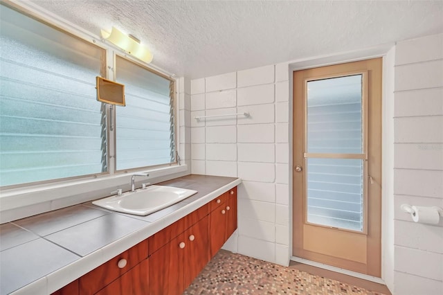 bathroom with vanity, tile walls, and a textured ceiling