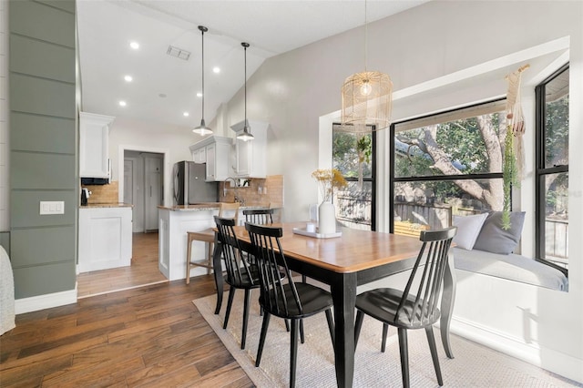 dining space with high vaulted ceiling and dark hardwood / wood-style floors