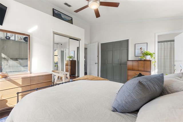 bedroom featuring lofted ceiling, ceiling fan, ensuite bathroom, ornamental molding, and multiple closets