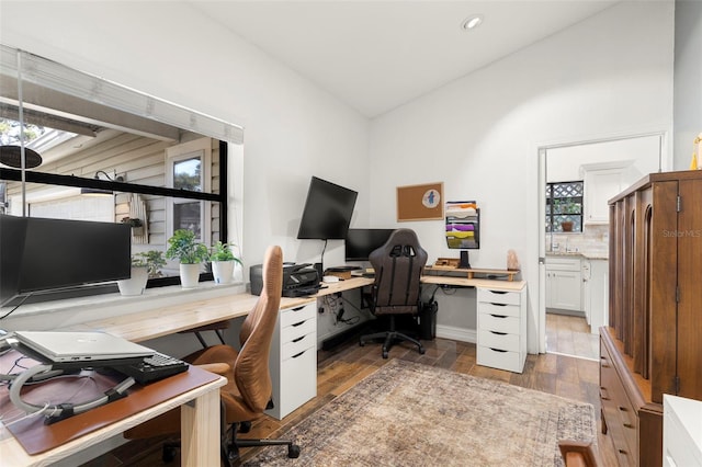 office with lofted ceiling and dark wood-type flooring