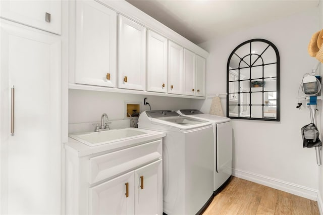 laundry area with cabinets, light hardwood / wood-style floors, sink, and washing machine and clothes dryer