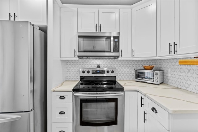 kitchen featuring stainless steel appliances, white cabinetry, tasteful backsplash, and light stone counters