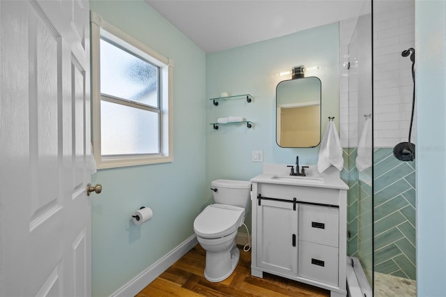 bathroom with hardwood / wood-style floors, vanity, a tile shower, and toilet