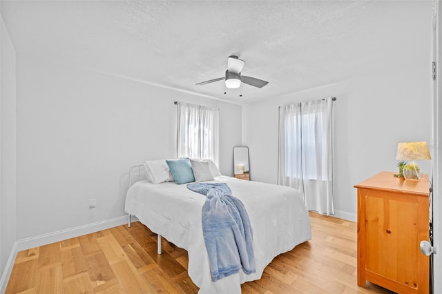 bedroom featuring ceiling fan, hardwood / wood-style flooring, and a textured ceiling