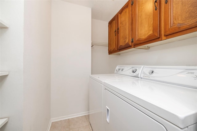 clothes washing area featuring cabinets, separate washer and dryer, and light tile patterned floors