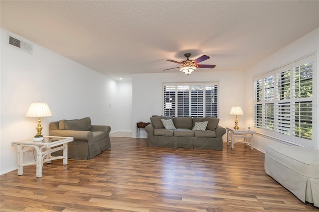 living room with hardwood / wood-style flooring, ceiling fan, and a textured ceiling