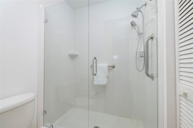 bathroom featuring a shower with door and toilet