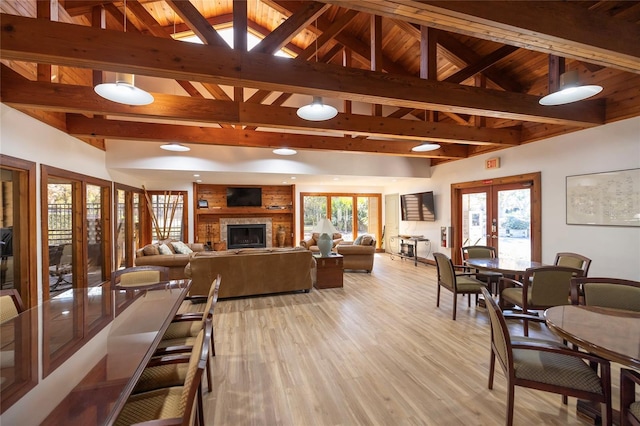 living room featuring french doors, wood ceiling, lofted ceiling with beams, a fireplace, and light hardwood / wood-style floors