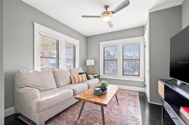 living room featuring dark wood-type flooring and ceiling fan