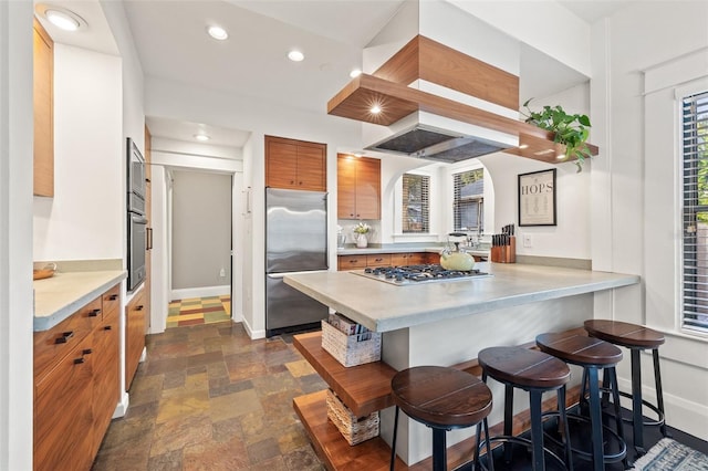 kitchen featuring custom range hood, a kitchen breakfast bar, kitchen peninsula, and appliances with stainless steel finishes