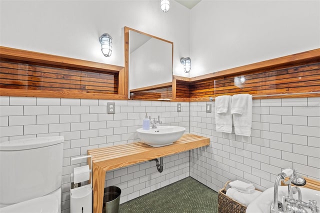 bathroom featuring toilet, sink, and tile walls