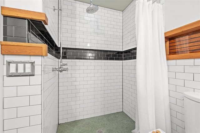 bathroom with tile walls, toilet, and walk in shower