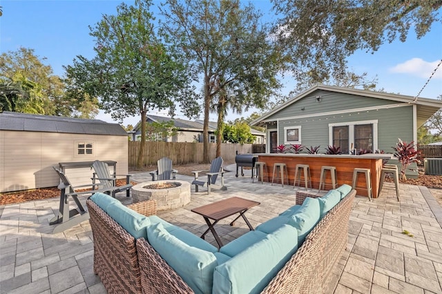 view of patio / terrace with a bar, a storage unit, and an outdoor living space with a fire pit