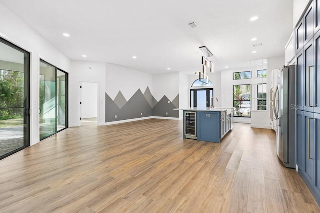 interior space featuring indoor wet bar, beverage cooler, and light hardwood / wood-style flooring