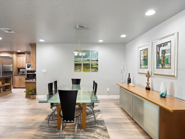 dining space featuring a textured ceiling and light hardwood / wood-style floors