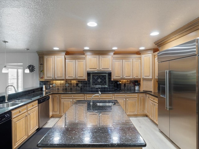 kitchen featuring stainless steel appliances, hanging light fixtures, sink, and light brown cabinetry