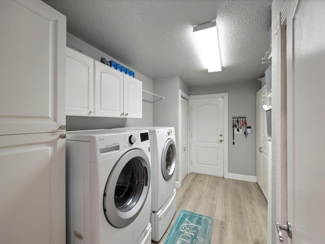 laundry room with cabinets, light hardwood / wood-style floors, washer and dryer, and a textured ceiling