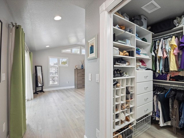 walk in closet featuring vaulted ceiling and light wood-type flooring