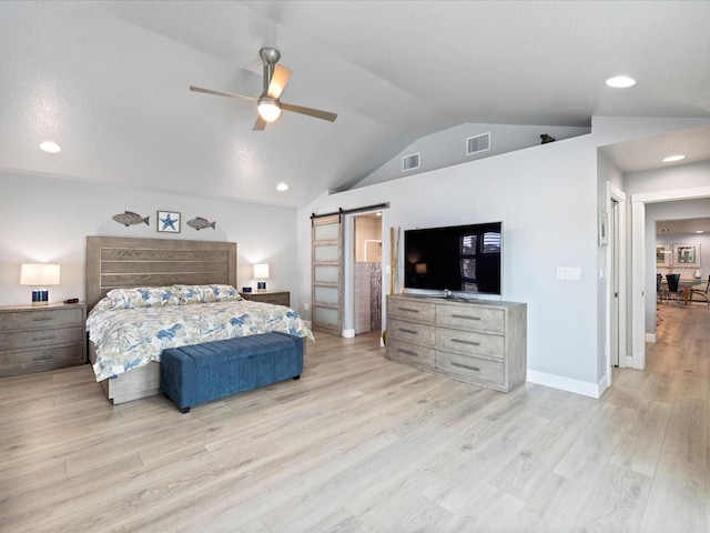 bedroom featuring ceiling fan, lofted ceiling, a barn door, and light hardwood / wood-style flooring