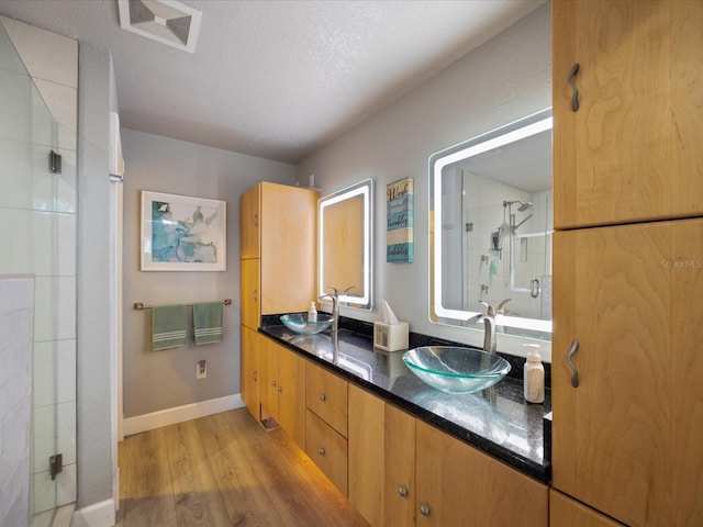 bathroom with vanity, hardwood / wood-style floors, a textured ceiling, and a shower with shower door