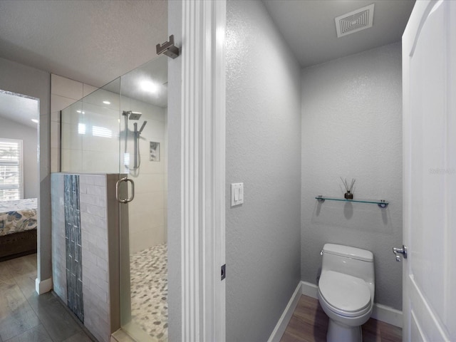 bathroom with wood-type flooring, an enclosed shower, and toilet