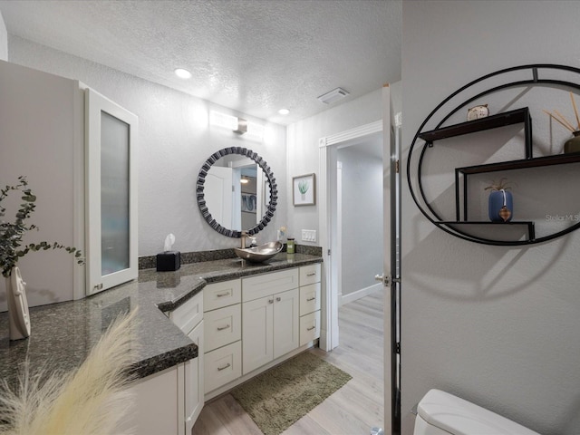 bathroom with wood-type flooring, toilet, a textured ceiling, and vanity